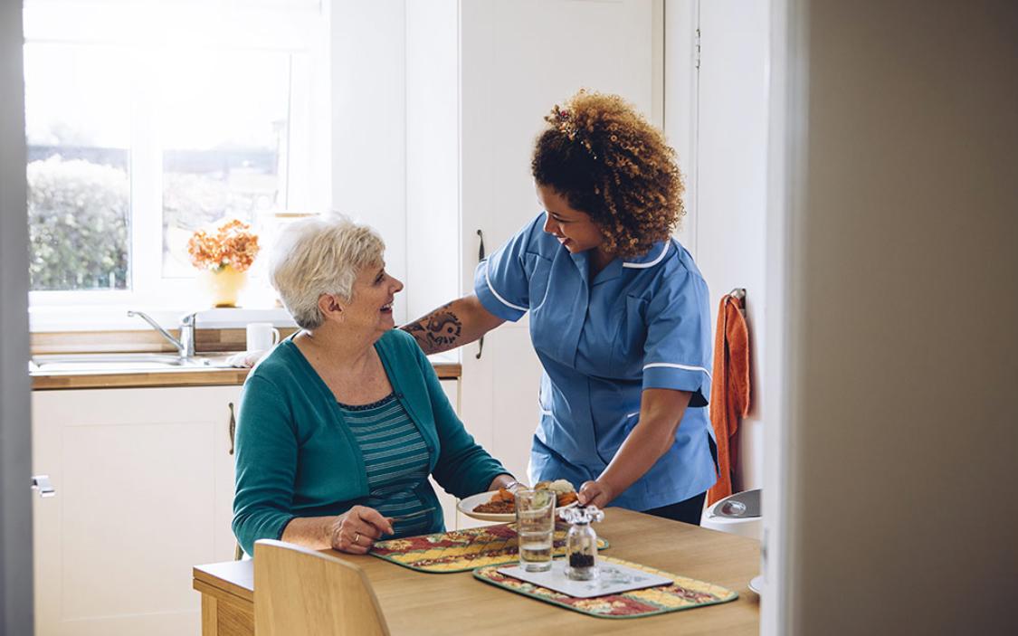 Senior receiving meal assistance from caregiver