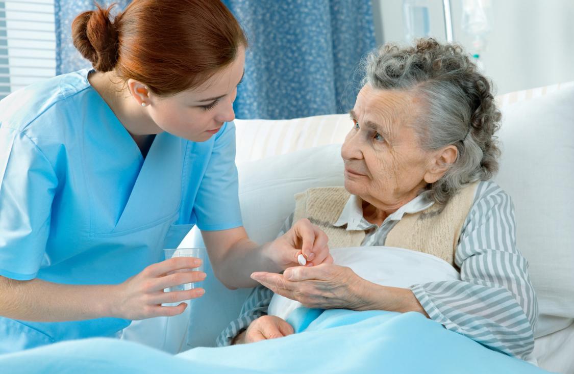 Caregiver administering medication to elderly patient